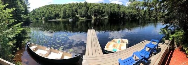 A wooden dock extending into a calm lake surrounded by dense forest.
