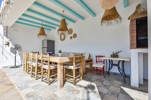 A dining area with a wooden table and chairs, a fan, and a small potted plant.