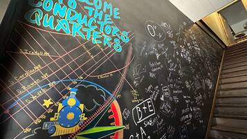 A wall with a chalkboard featuring a train track design and various names and dates.