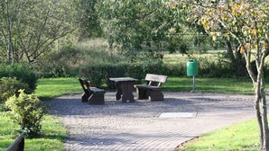 Een verhard pad dat leidt naar een parkgedeelte met een bank en een tafel.