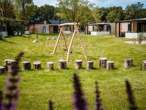 Relax in a serene outdoor space surrounded by lush greenery and a wooden swing set.