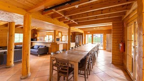 Une cabane en bois spacieuse, dotée d’une grande table à manger, d’un coin cuisine et d’un espace salon confortable.
