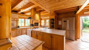 Une cuisine spacieuse avec des meubles en bois, un grand îlot central et un réfrigérateur en acier inoxydable.