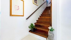 A wooden staircase with a handrail, two potted plants, and framed artwork on the walls. - Villino D'Agostino · Beachside 2-room villa flat, parking & 2 baths (Francavilla al mare)