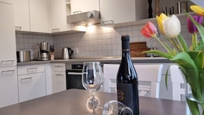 A modern kitchen with white cabinets, a stainless steel range hood, and a wine bottle on the counter. - Kommodig Utkiek Modern Retreat (Zingst)