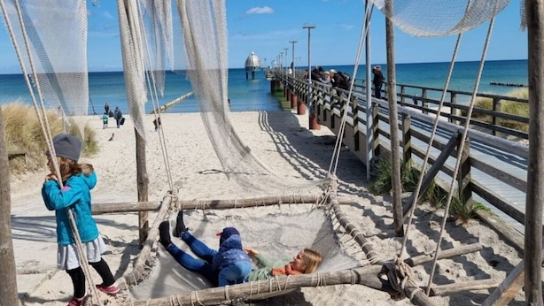A beach with a wooden walkway and a rope hammock. - Kommodig Utkiek Modern Retreat (Zingst)