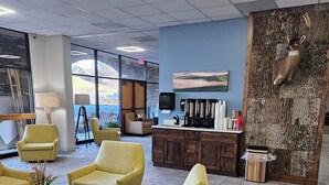 Un espace de détente moderne avec des fauteuils jaunes, un coin café et une grande fenêtre donnant sur l’extérieur.