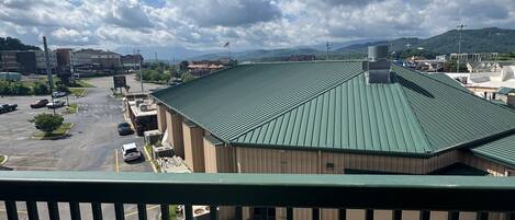 A view from a balcony overlooking a parking lot and a building with a green roof.