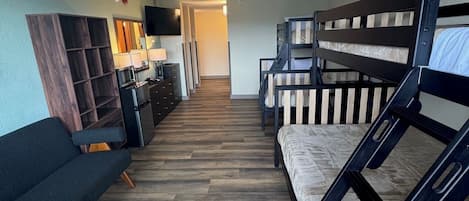 Une pièce avec un canapé, des lits superposés, une télévision et un plancher en bois.