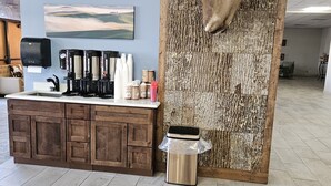 Un espace d’accueil comprenant un meuble en bois, une machine à café et une poubelle.