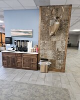 A reception area with a wooden cabinet, a coffee machine, and a trash bin.