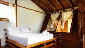 Une pièce avec un cadre en bois, comprenant un lit, une fenêtre avec des rideaux et un plancher en bois.