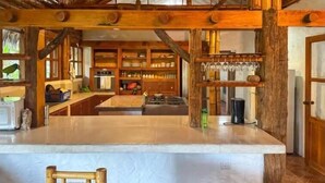 Une cuisine rustique avec des poutres en bois, un îlot central et un porte-verres suspendu.