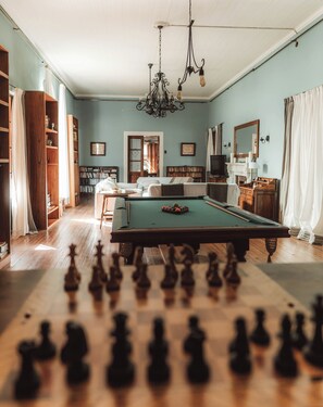Una habitación amplia con mesa de billar, chimenea y un espejo grande.
