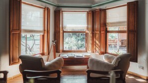 A corner room with large windows, wooden furniture, and a ceiling fan. - Estancia La Violeta (Chajarí)