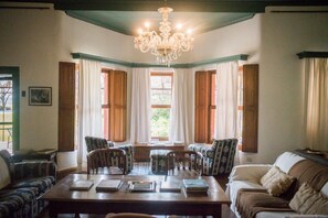 Una habitación con una mesa de comedor rodeada de sillas, un sofá y una araña.