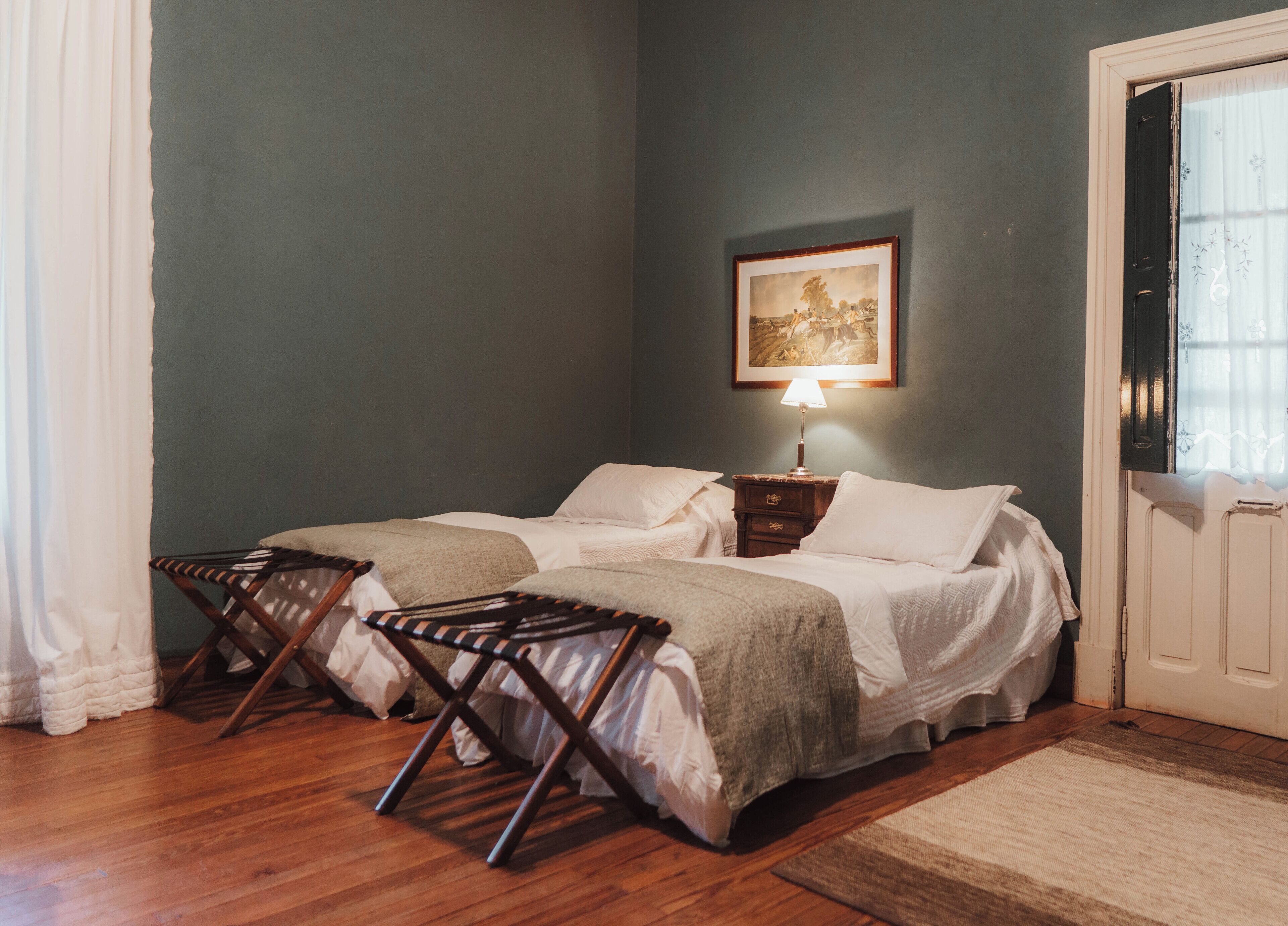 Un dormitorio con cama, dos mesitas de noche, una lámpara, una silla y una puerta.