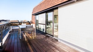 A wooden deck with a glass door leading to a room with a white wall and a window. - Apartment Near Oostduinkerke Nature Reserve (Koksijde)
