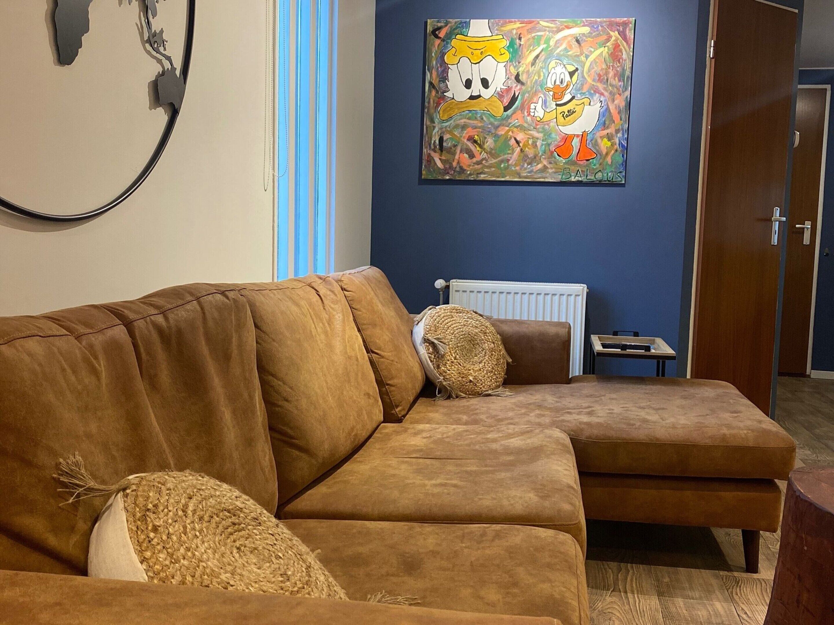 Ein braunes Ledersofa mit einem gewebten Zierkissen, einem kleinen Beistelltisch und einem Heizkörper an einer blauen Wand.