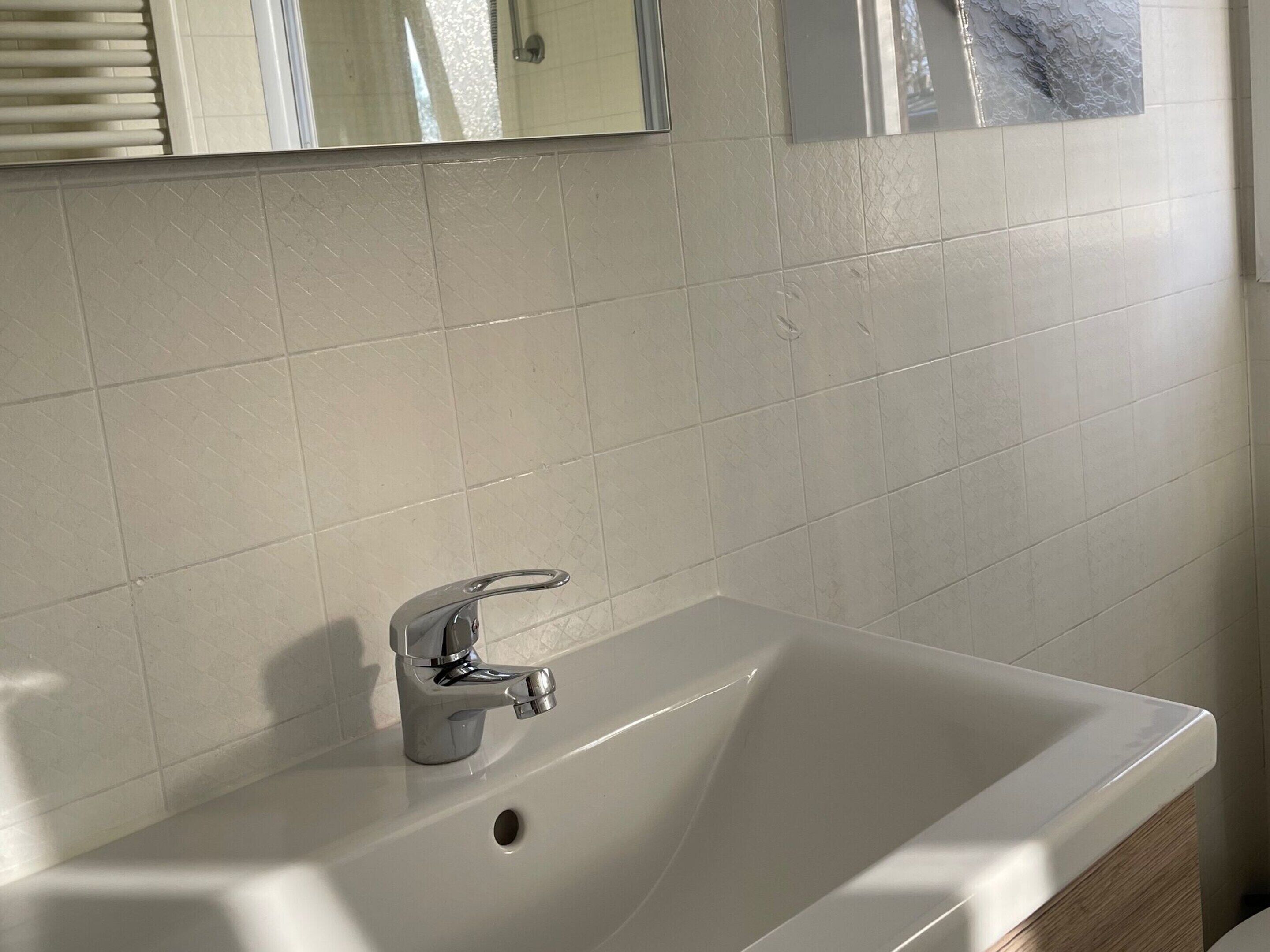 A bathroom with a white sink, chrome faucet, and a mirror above it.