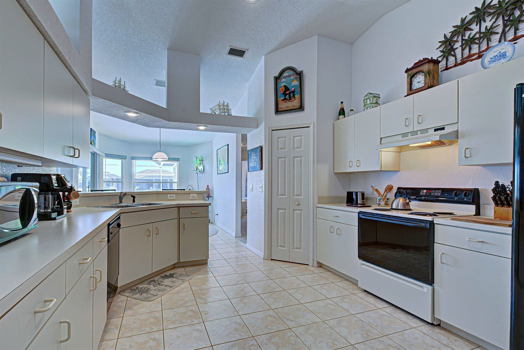 A modern kitchen with white cabinetry, a central island, a built-in oven, and a microwave.