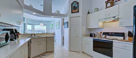 A modern kitchen with white cabinetry, a central island, a built-in oven, and a microwave.