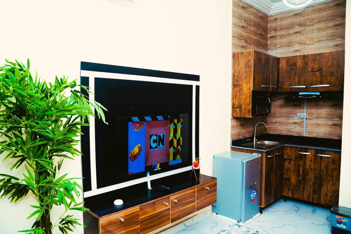 Eine moderne Küche mit Holzausstattung, einer eingebauten Mikrowelle und einem kleinen Kühlschrank.