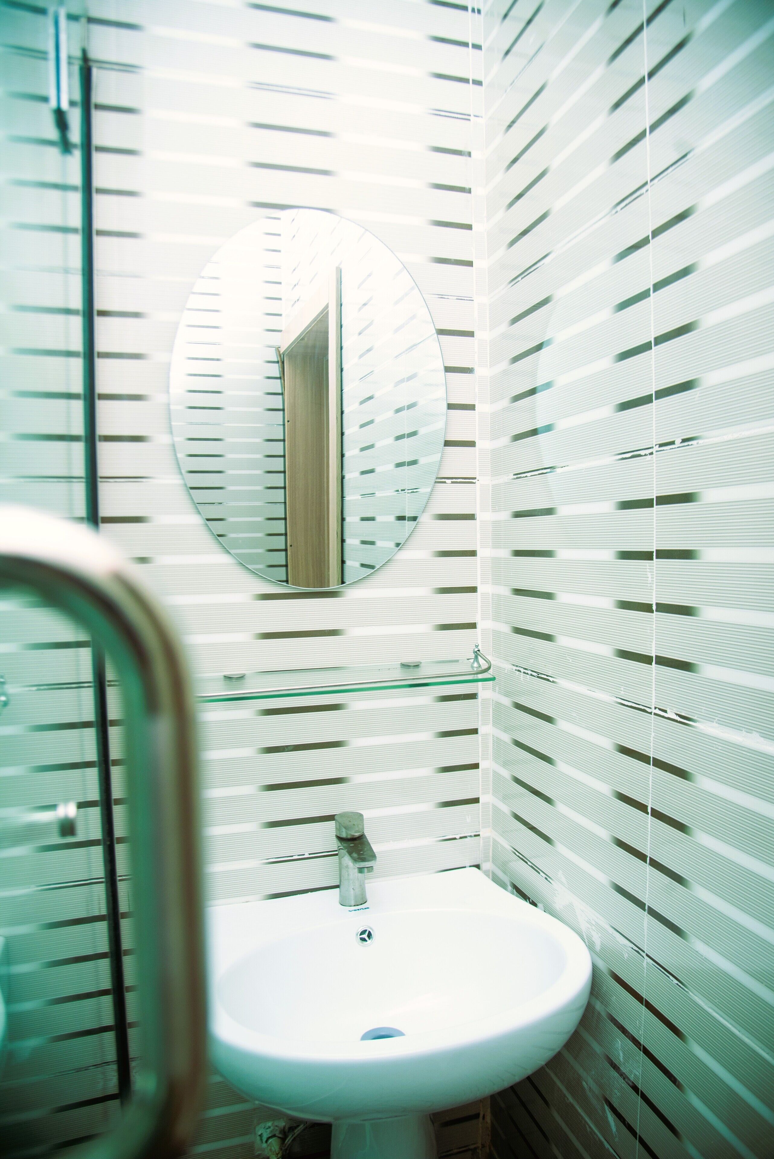 A bathroom with a round mirror, a sink, and a toilet.