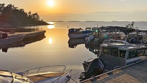 Una marina con barche ormeggiate, un molo di legno e un tramonto sullo sfondo.