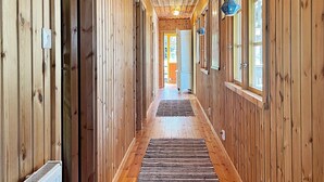Un corridoio in legno con termosifone, un tappeto e una porta in fondo.