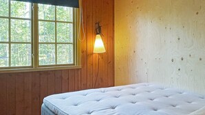 Una camera da letto con un letto, pareti in legno, una finestra e un lampadario a parete.