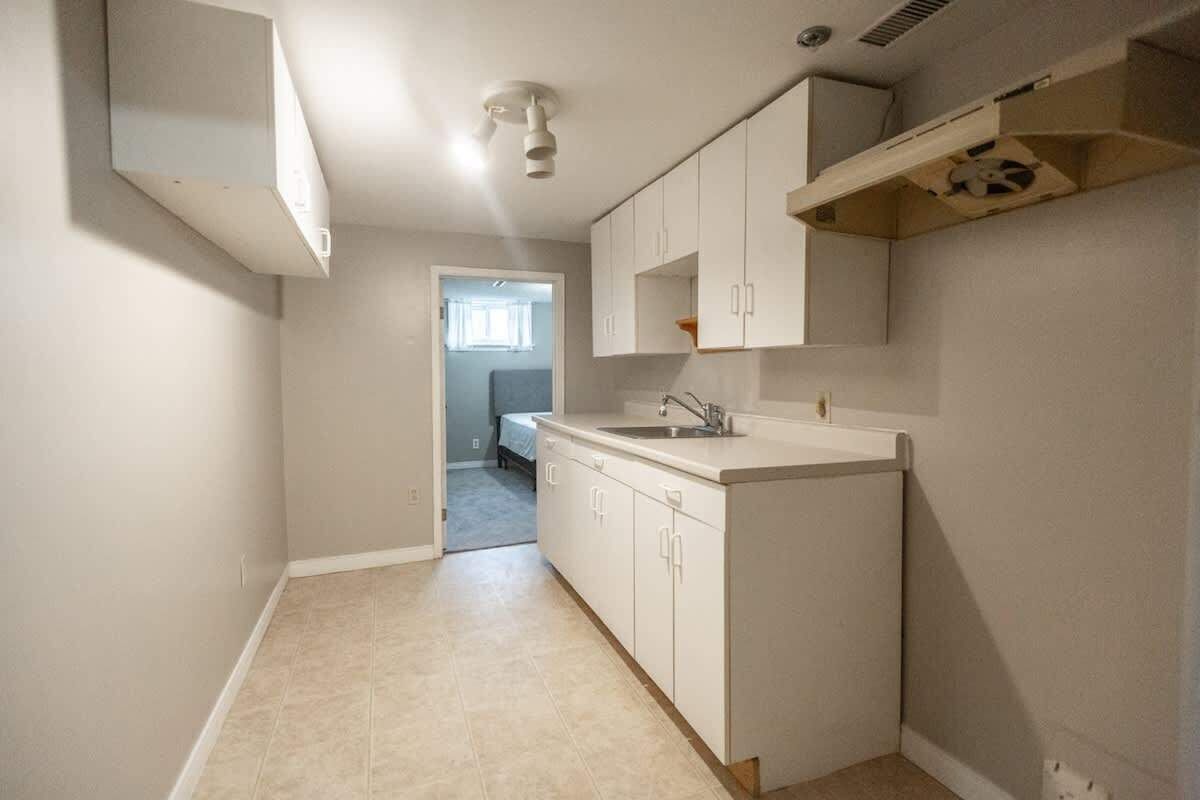 A kitchen with white cabinets, a countertop sink, and a built-in oven.