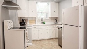 A modern kitchen with white cabinetry, a built-in oven, a refrigerator, and a window providing natural light.
