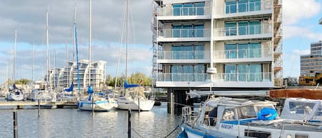 Ein Yachthafen mit mehreren angossenen Booten, ein sich befindendes im Bau befindliches Gebäude mit Gerüst, und ein klarer Himmel.