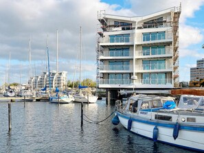 A marina with multiple boats docked, a building under construction with scaffolding, and a clear sky. - Holiday Home in Wendtorf (Wendtorf)