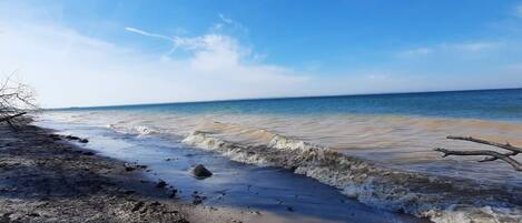 Une plage avec des vagues, un ciel dégagé et un horizon lointain.