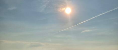 Une plage avec un ciel dégagé, une personne qui se promène et une structure visible au loin.