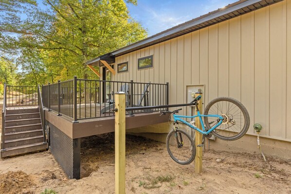A building with a covered outdoor area, a bicycle, and a staircase leading to a deck.