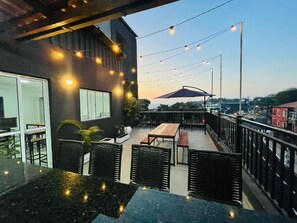 An outdoor patio with tables and chairs, string lights, and a view of the cityscape. - FlyNow Studios: Aeroporto, SP Expo e Metrô (São Paulo)