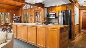 A spacious kitchen with wooden cabinetry, a central island, and stainless steel appliances. - Hall's Haven - Your Home away from Home (Bellaire)