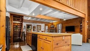 L’intérieur d’une cabane en bois comprend un espace cuisine équipé de meubles de rangement en bois, d’un réfrigérateur et d’un four encastré.