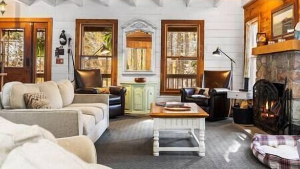 Un salon chaleureux avec une cheminée, des poutres en bois et de grandes fenêtres.