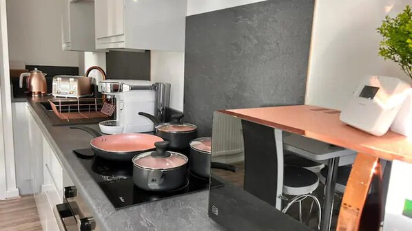 A modern kitchen with a black countertop, stainless steel appliances, and a small dining table.