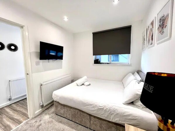 A modern bedroom with a large bed, a flat-screen TV, a window with a view, and a radiator.