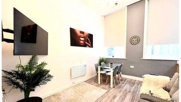 Un salon moderne avec un téléviseur à écran plat, une table à manger avec des chaises, un canapé et une grande plante en pot.
