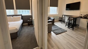 A modern hotel room with a bed, a desk, a TV, and a chandelier. - Lovely 2-bed Apartment in Liverpool (Liverpool)