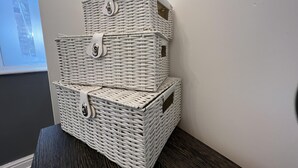 Three white wicker baskets stacked on a dark wooden table against a white wall. - Lovely 2-bed Apartment in Liverpool (Liverpool)