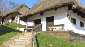 A row of traditional thatched-roof cottages with white walls and wooden doors, connected by a grassy path. - Kellerstockl am Hamerlberg/strem (Strem)