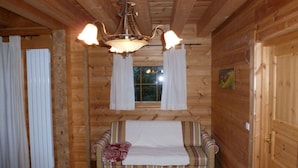 Una habitación acogedora con techo de madera, un sofá con funda estampada y una ventana con cortinas.