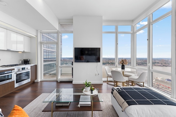 Un appartement moderne doté d’une cuisine, d’un coin repas et d’une grande fenêtre offrant une vue sur la ville.